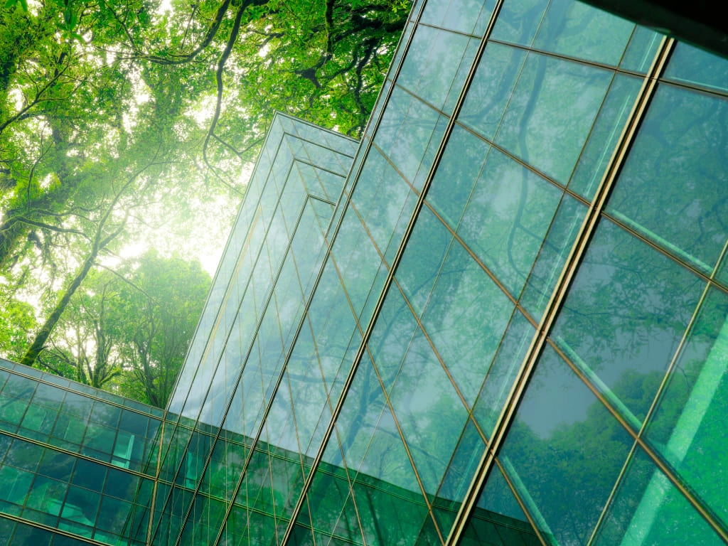 Modern glass building reflecting green trees